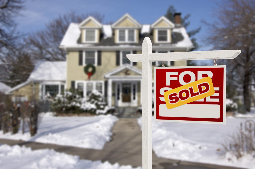 Sold Home For Sale Real Estate Sign in Front of Beautiful New House in the Snow.